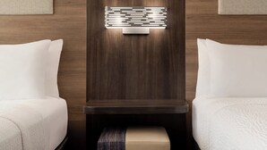 Habitación de hotel con dos camas, cabecero de madera y una lámpara moderna de pared.