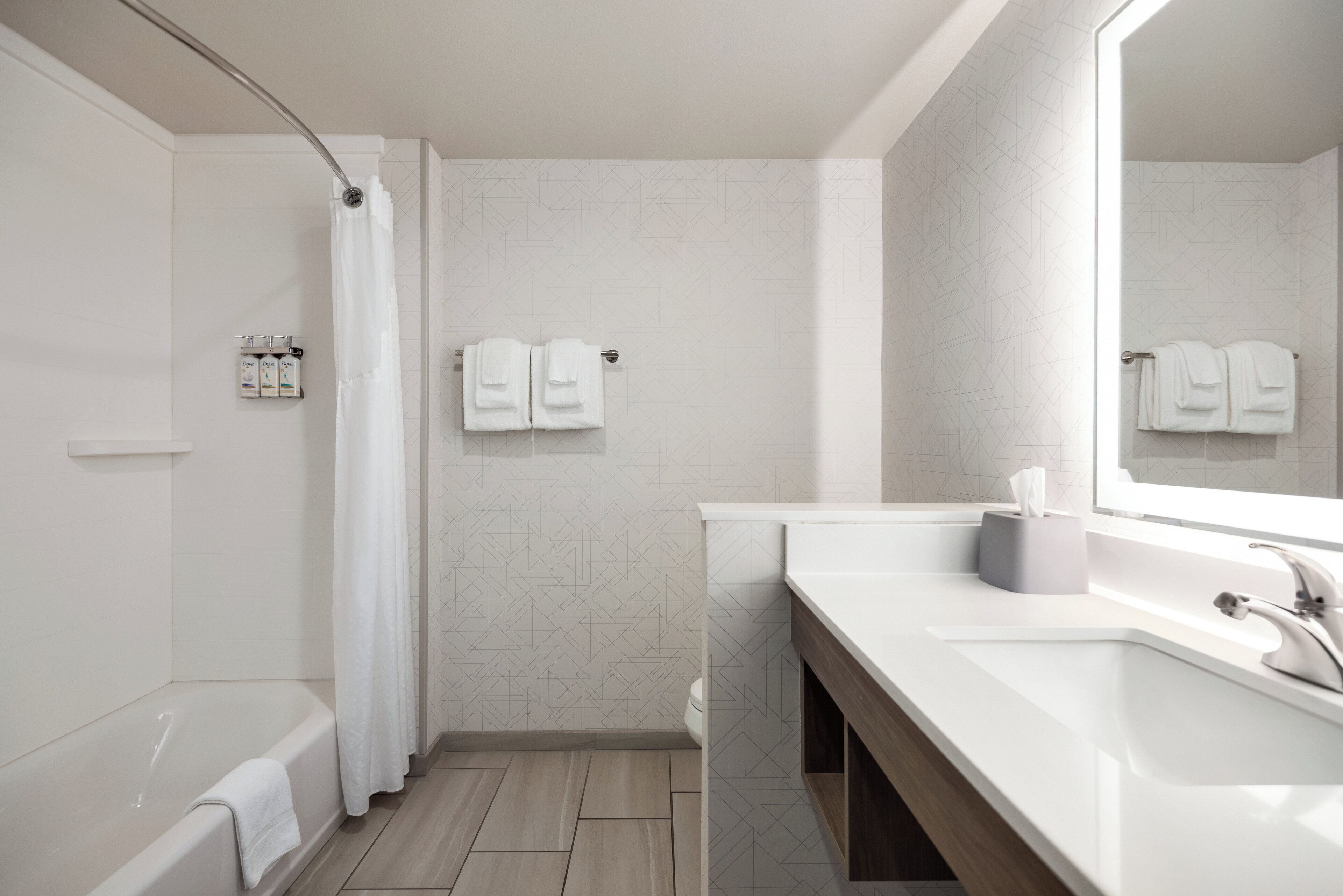 Un baño moderno con bañera, ducha y tocador con espejo.