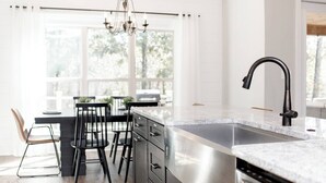 A modern kitchen with a large island, stainless steel appliances, and a black faucet. - Luxe 3BR Family Stay | Fenced Yard | Prime WR (Kathleen)