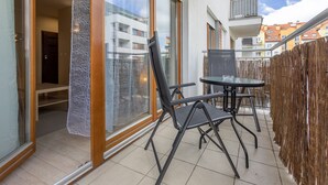 Ein Balkon mit Glastür, einem Tisch und zwei Stühlen.