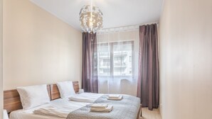 Ein ordentlich bezogenes Bett mit einer gesteppten Decke, einem Nachttisch und einer hängenden Leuchte.