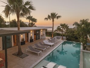 A modern poolside area with lounge chairs, a pool, and palm trees.