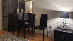Ett kompakt bostadsutrymme med en matplats, ett kylskåp, en spegel och en lampa.