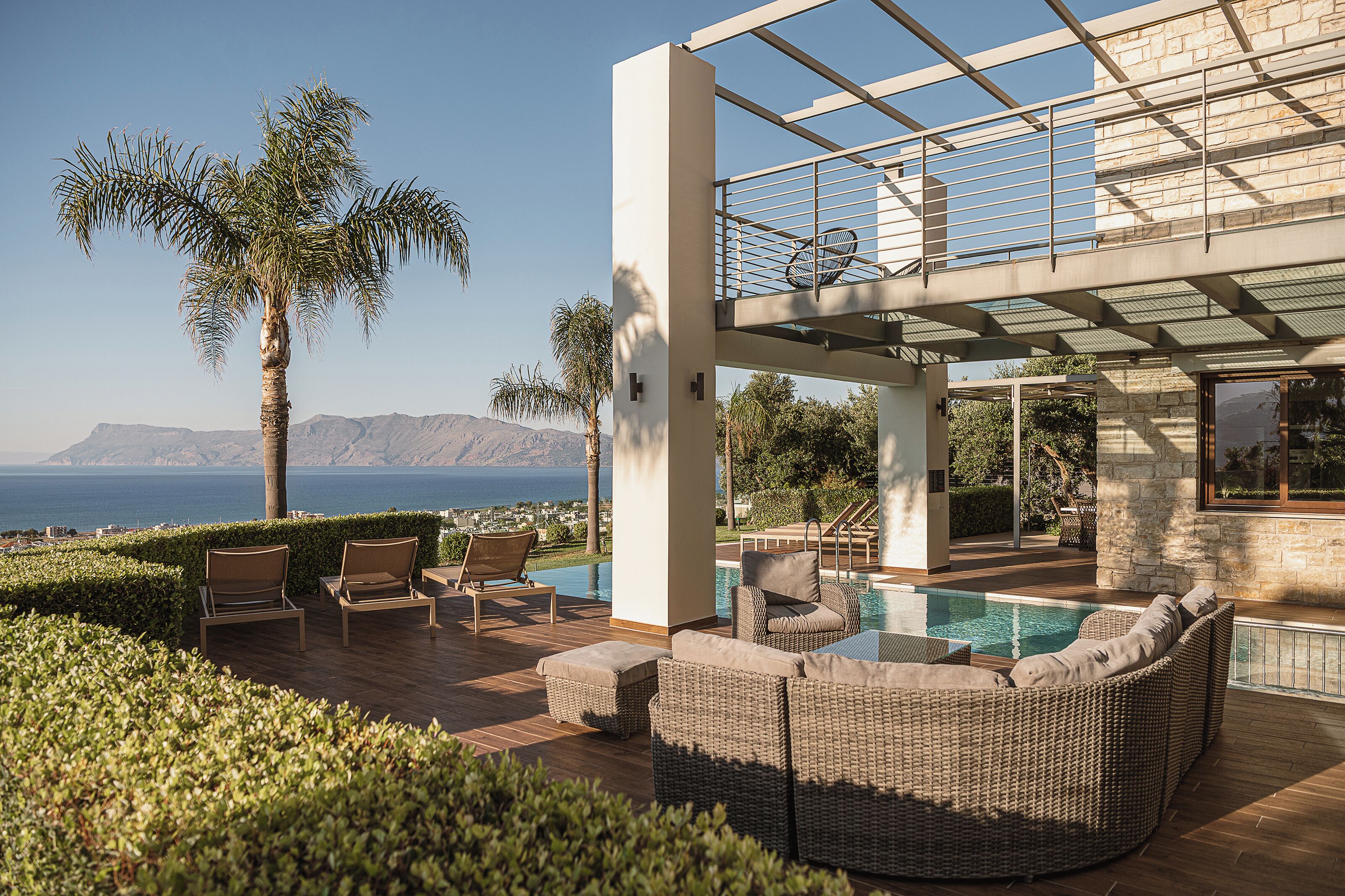 A modern outdoor pool area with lounge chairs and a view of the sea.