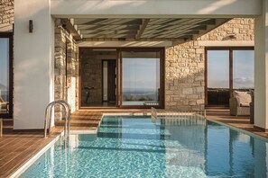Una piscina con un muro de piedra y vista al mar.