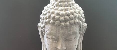 A stone Buddha statue seated on a bed of smooth pebbles.