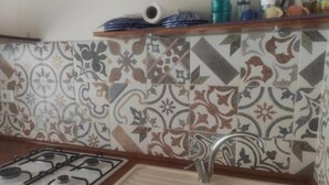 A kitchen with a gas stove, a sink, and a decorative backsplash. - Mary's Niche (Bisceglie)