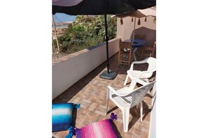 Relax on the balcony with a view of the surrounding landscape, featuring a comfortable chair and a small table.