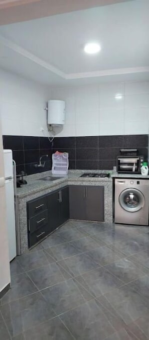 Kitchenette with oven, washing machine, and modern cabinetry.