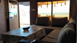 Ein Zimmer mit einer Couch, einem Tisch und Blick auf den Strand durch ein Fenster.