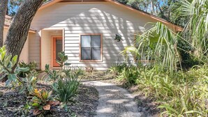 A single-story house with a front door, a window with shutters, and a small porch area. - Coastal Oaks - Atlantic Beach home just 3 blocks from the beach (Atlantic Beach)
