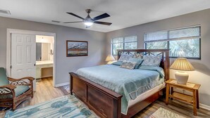 A bedroom with a bed, a ceiling fan, a nightstand, a chair, and a window with blinds. - Coastal Oaks - Atlantic Beach home just 3 blocks from the beach (Atlantic Beach)
