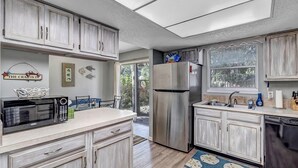 A kitchen with light wood cabinets, a stainless steel refrigerator, a microwave, and a sink. - Coastal Oaks - Atlantic Beach home just 3 blocks from the beach (Atlantic Beach)