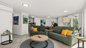 A modern living room with a sofa, armchairs, a coffee table, and artwork on the walls.
