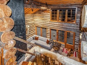A log cabin interior with a sofa set, a dog, and a window with multiple panes.