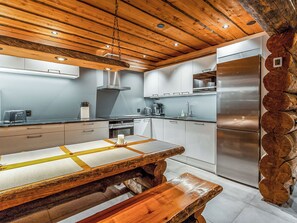 A modern kitchen with wooden ceiling beams, stainless steel appliances, and a central island with a wooden top. - Kelohippu 2 by Interhome (Pelkosenniemi)