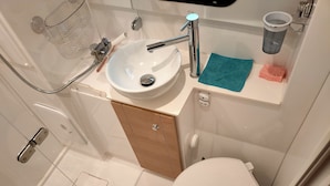 Een badkamer met een wit wastafel, toilet en douche.