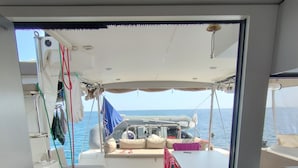 Een open deur naar een terras met uitzicht op zee, een tafel en een stopcontact.