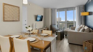 Una sala de estar moderna con comedor, un sofá y un televisor montado en la pared.