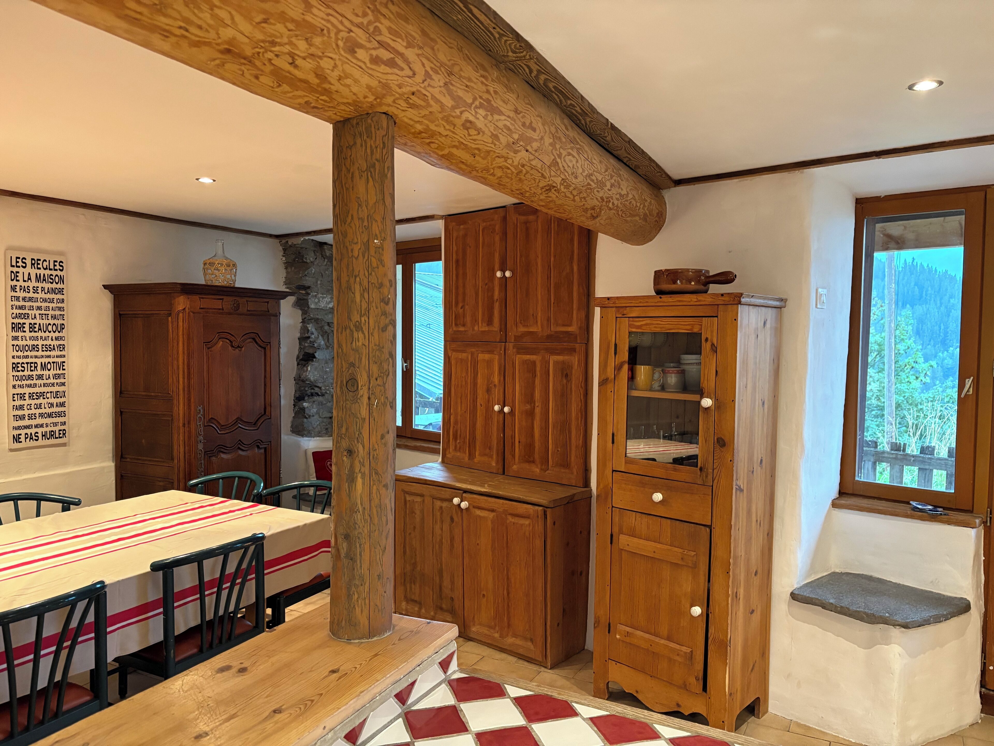 A wooden dining table with chairs, a wooden cabinet, and a stone ledge.