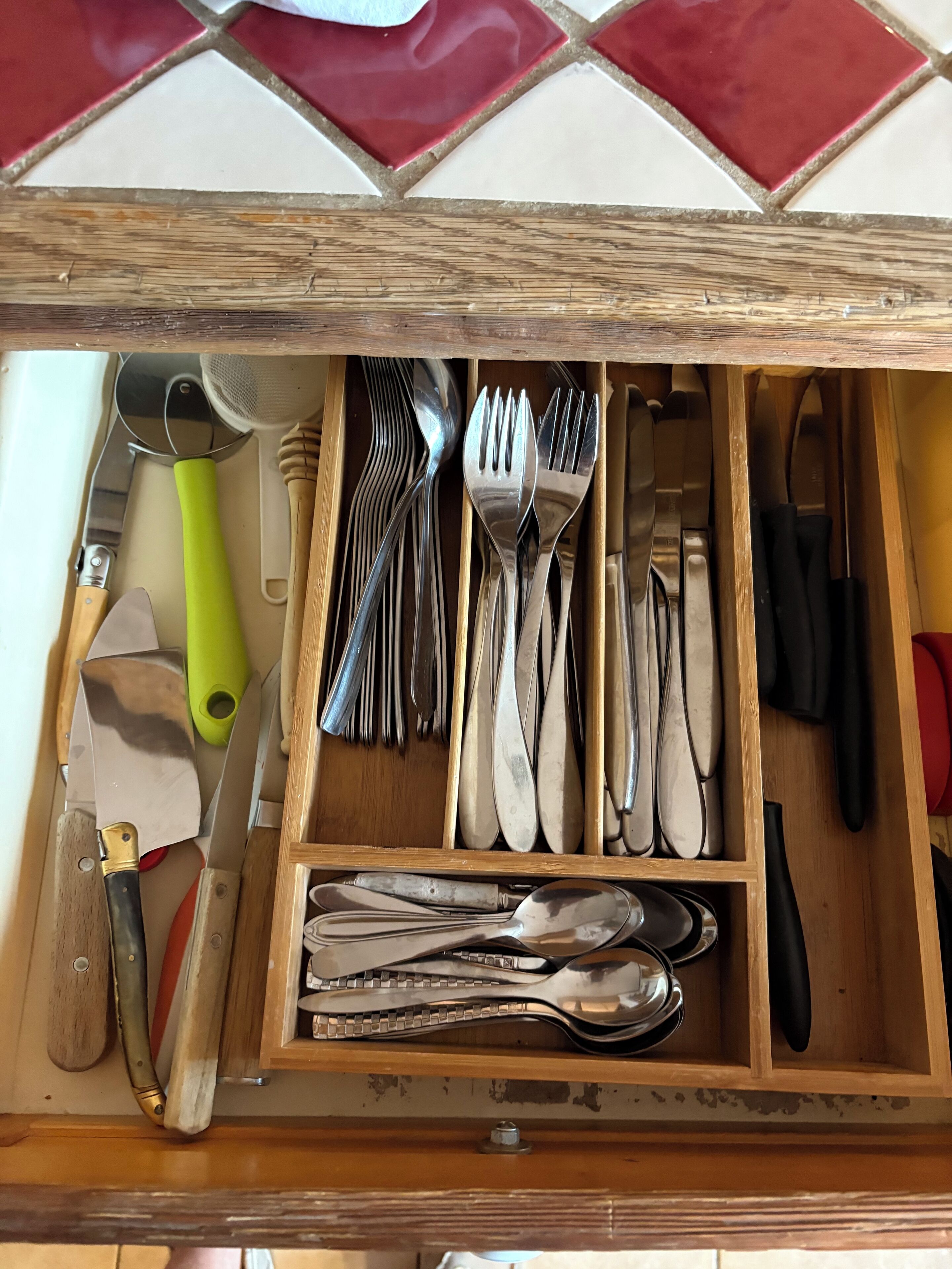 A drawer with various kitchen utensils including spoons, forks, and knives.