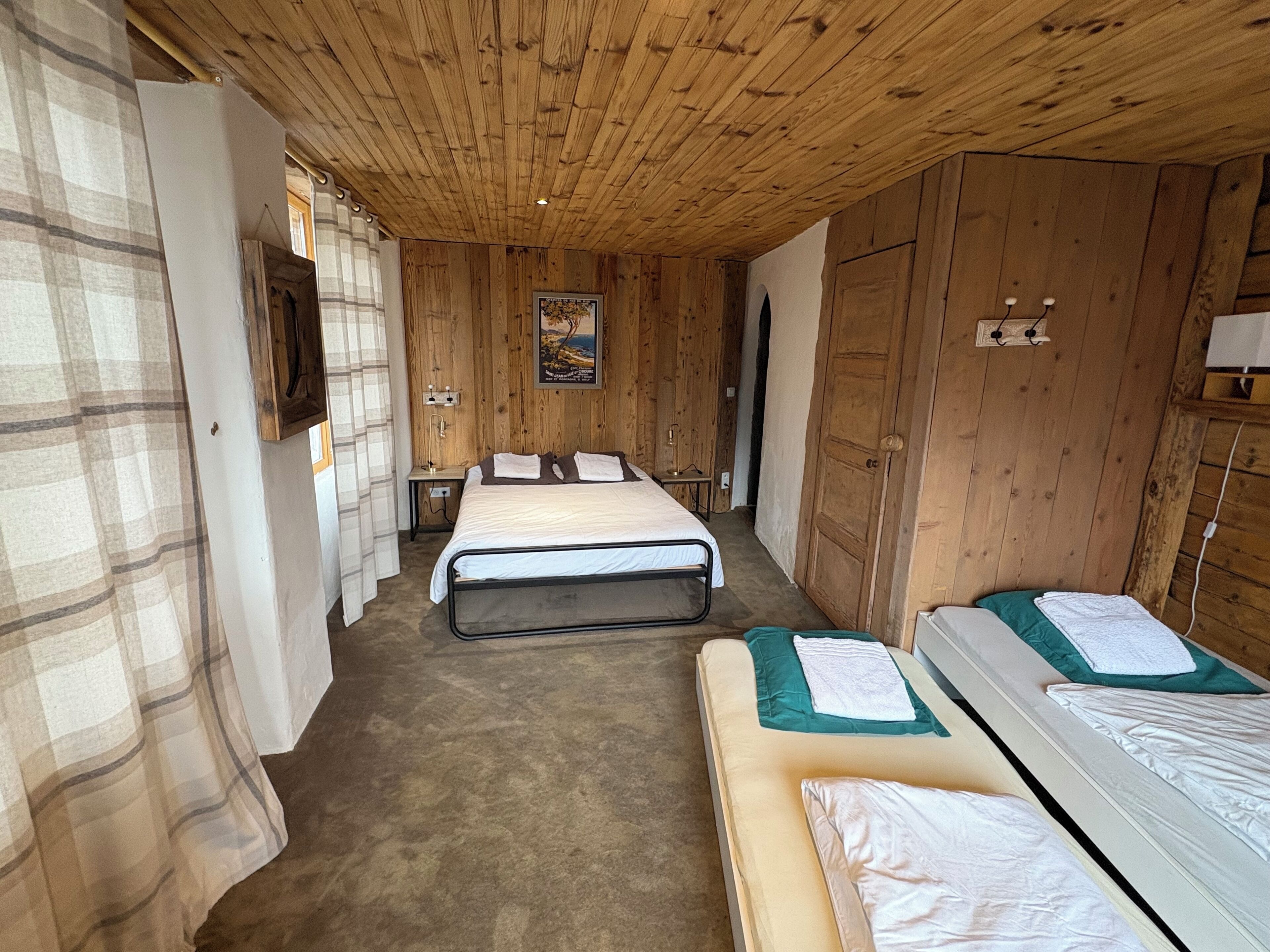 Una habitación con paneles de madera, dos camas, una mesita y un cuadro en la pared.