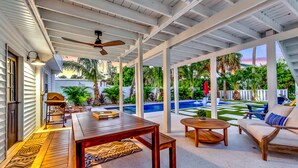 A covered outdoor patio with a wooden table, chairs, and a sofa. - Anna Maria Gem! Pool, Canal Views and Style! (Anna Maria)