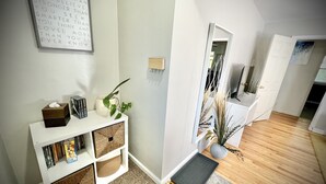 A modern living room with a white console table, bookshelves, a potted plant, and a framed inspirational quote on the wall. - Spacious Home 8 min to ND and Memorial Hospital (South Bend)