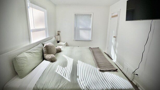 A bedroom with a bed, pillows, a bedside table, a lamp, and a TV mounted on the wall. - Spacious Home 8 min to ND and Memorial Hospital (South Bend)