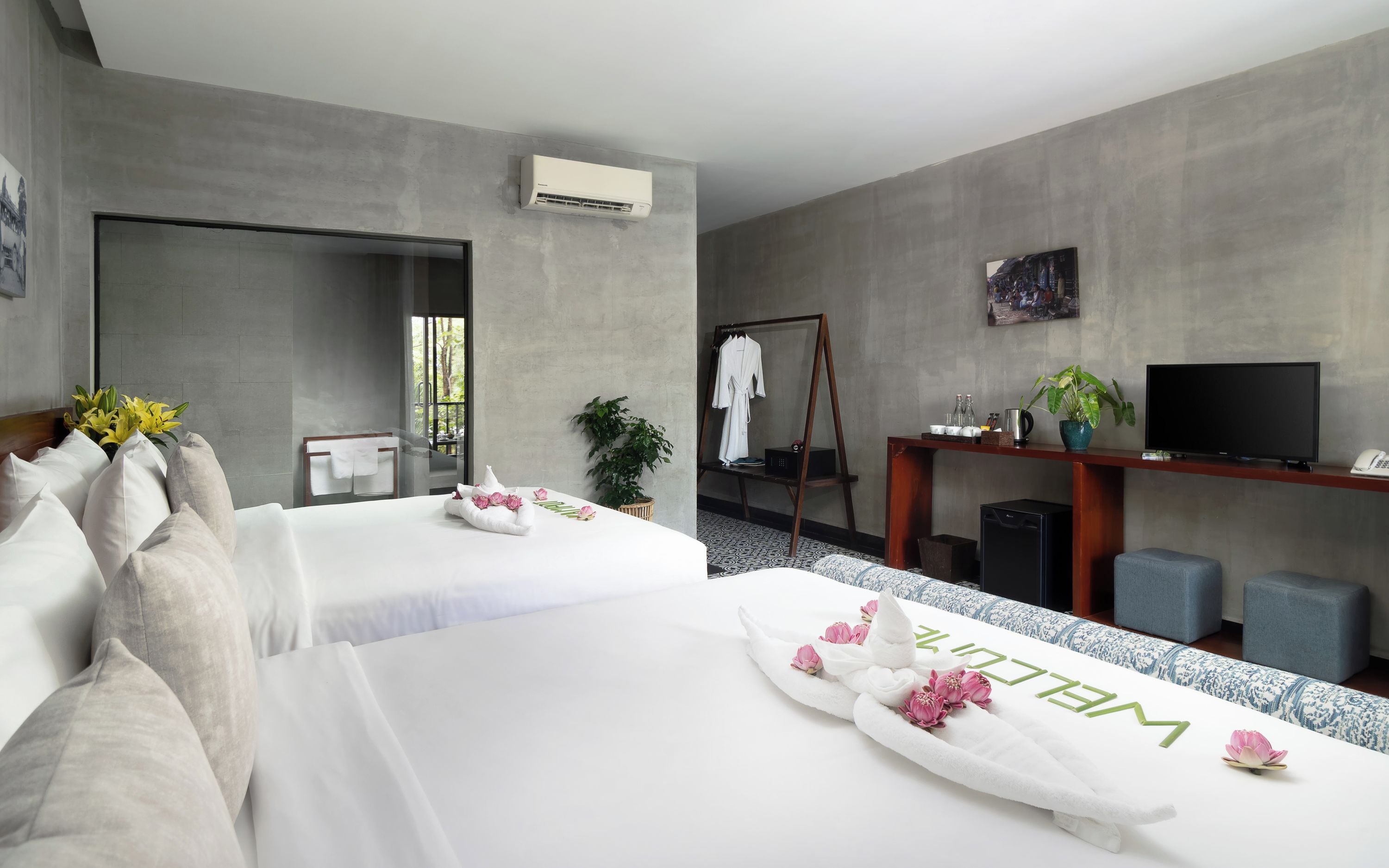 A hotel room with two beds, a TV, a desk, and a large mirror.