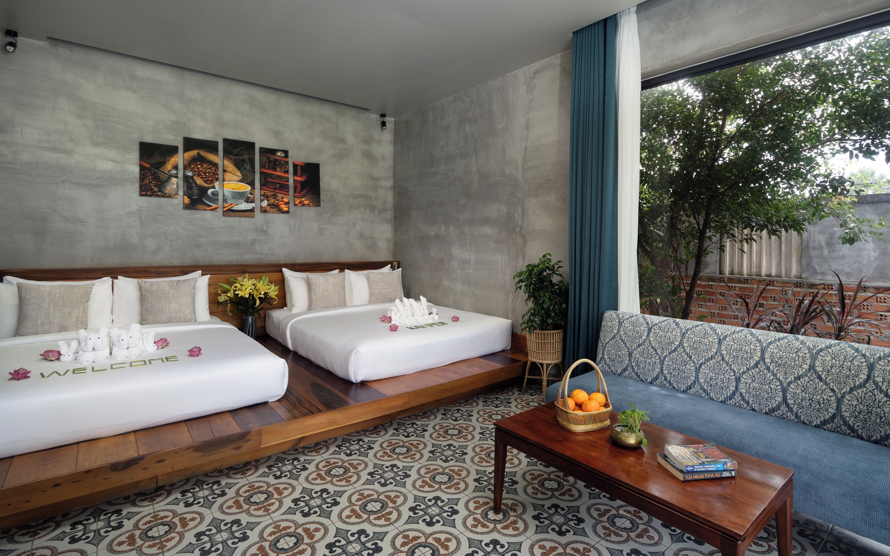 Une chambre d’hôtel avec deux lits, un canapé, une table basse et une vue sur l’extérieur.