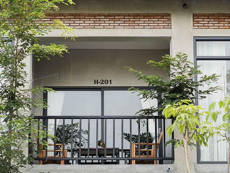 A building facade with a large window, a balcony with a railing, and a sign reading "H-201".