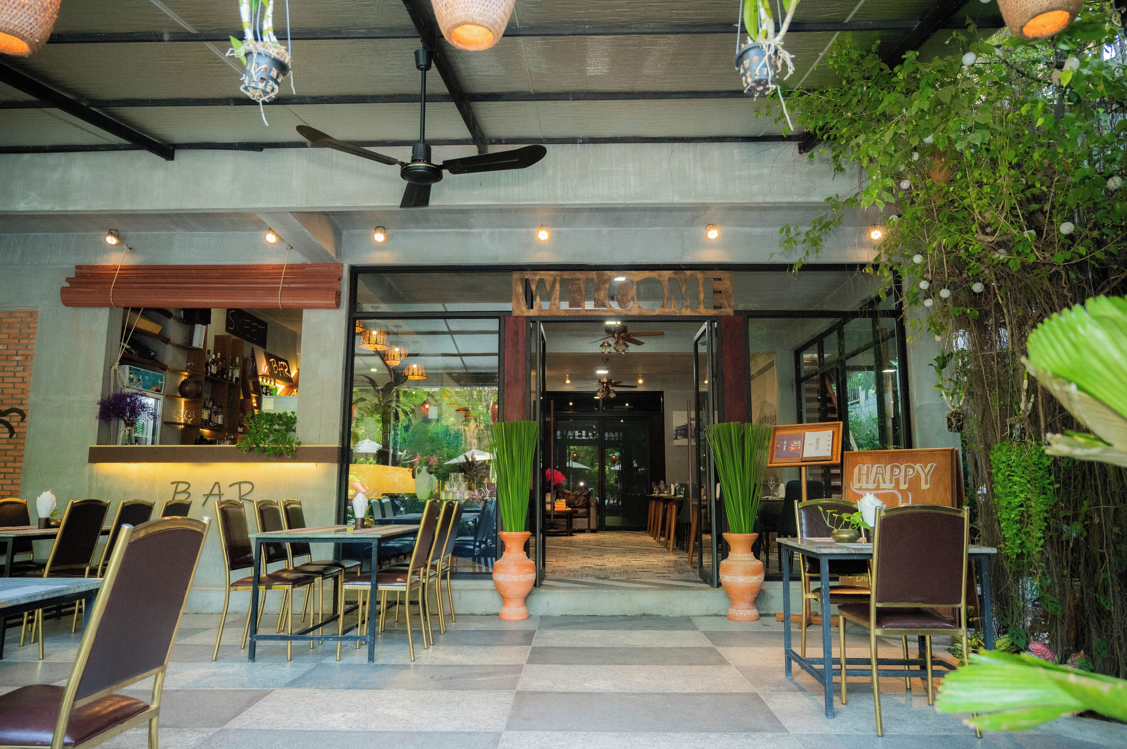 An indoor restaurant with a checkered floor, wooden furniture, and a 'WELCOME' sign.