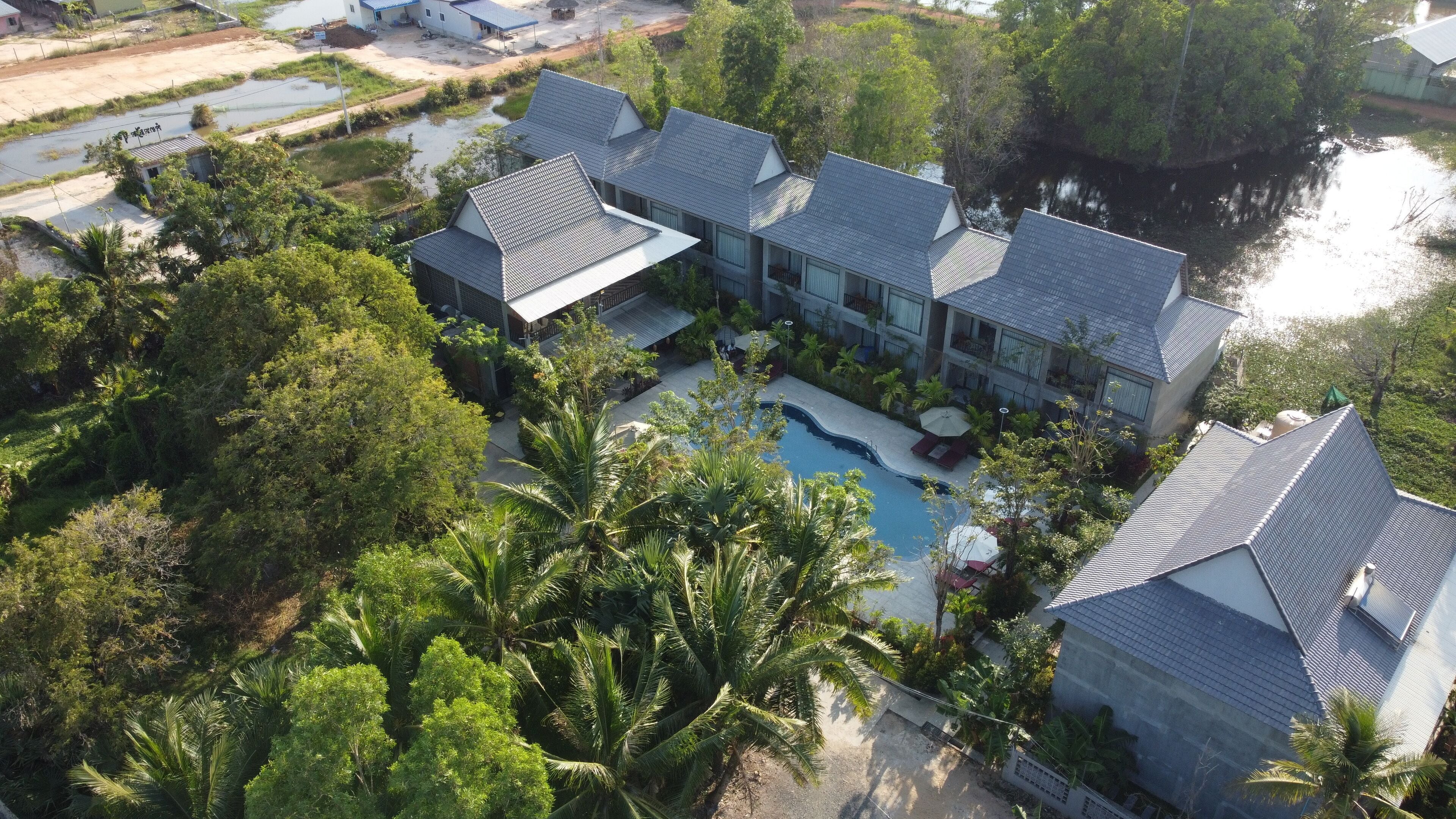 A large, modern hotel with multiple buildings, a swimming pool, and lush greenery.