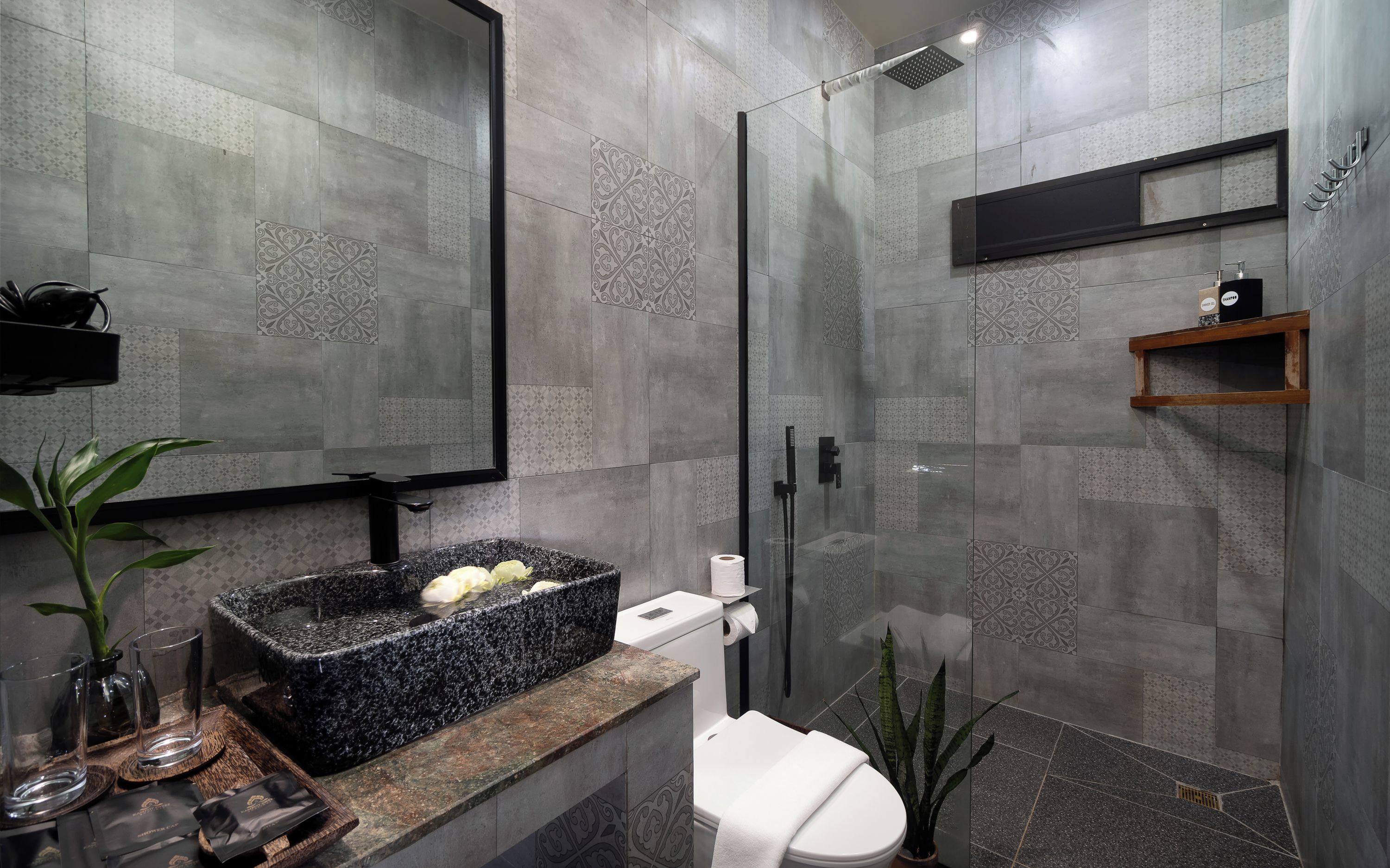 A modern bathroom with a granite sink, toilet, and shower.
