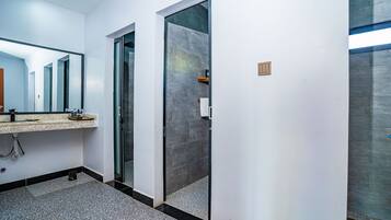 Un baño moderno con cabina de ducha de vidrio, un lavabo con encimera y un espejo.