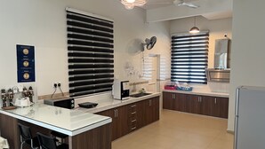 Una cocina moderna con una isla central, armarios de madera oscura, encimera blanca y horno empotrado.
