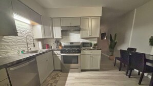 Una cucina moderna con lavastoviglie, forno, microonde e zona pranzo con sedie.