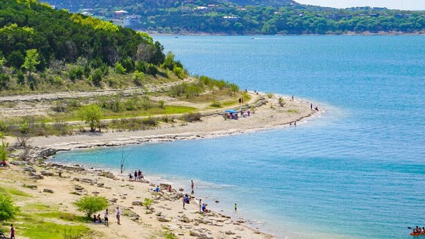 A coastal beach with people relaxing and kayaking.