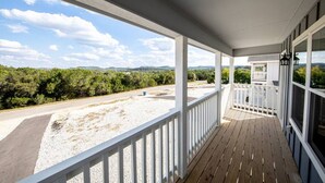 A covered porch with a view of a road and greenery.