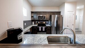 A compact kitchen with granite countertops, stainless steel appliances, and dark cabinetry.