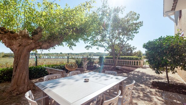 Un espacio al aire libre para comer con mesa y sillas, rodeado de árboles y vistas del paisaje.