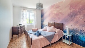 Un dormitorio con una cama grande, un tocador, una mesita de noche y un mural en la pared.