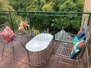 A balcony with metal chairs and a table, surrounded by a green metal railing. - Lovely Riverside Perthshire Flat - Sleeps 8 (Blairgowrie)