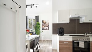 A modern kitchen with white cabinets, a built-in oven, and a coffee maker. - Apartment an der Theresienwiese (München)