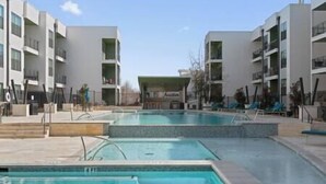 Um hotel moderno com piscina central, várias varandas e céu limpo.