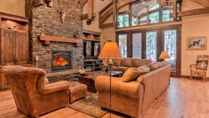A rustic living room with a stone fireplace, leather sofas, and wooden beams. - AC, gourmet kitchen, pet friendly, Luxury (Sunriver)