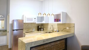 A modern kitchen with a stainless steel refrigerator, granite countertops, a built-in sink, and pendant lighting. - Popotla Villa 203 (PLAYAS DE ROSARITO)
