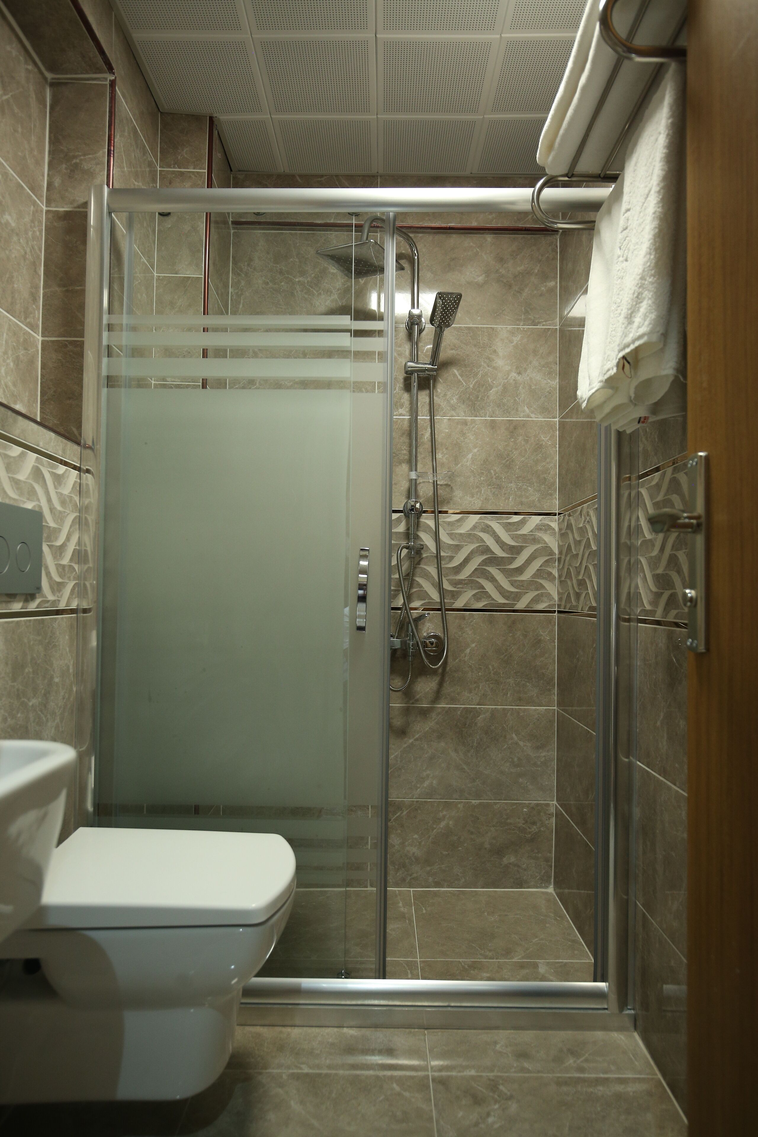 Un baño moderno con ducha de vidrio, inodoro y toallero.