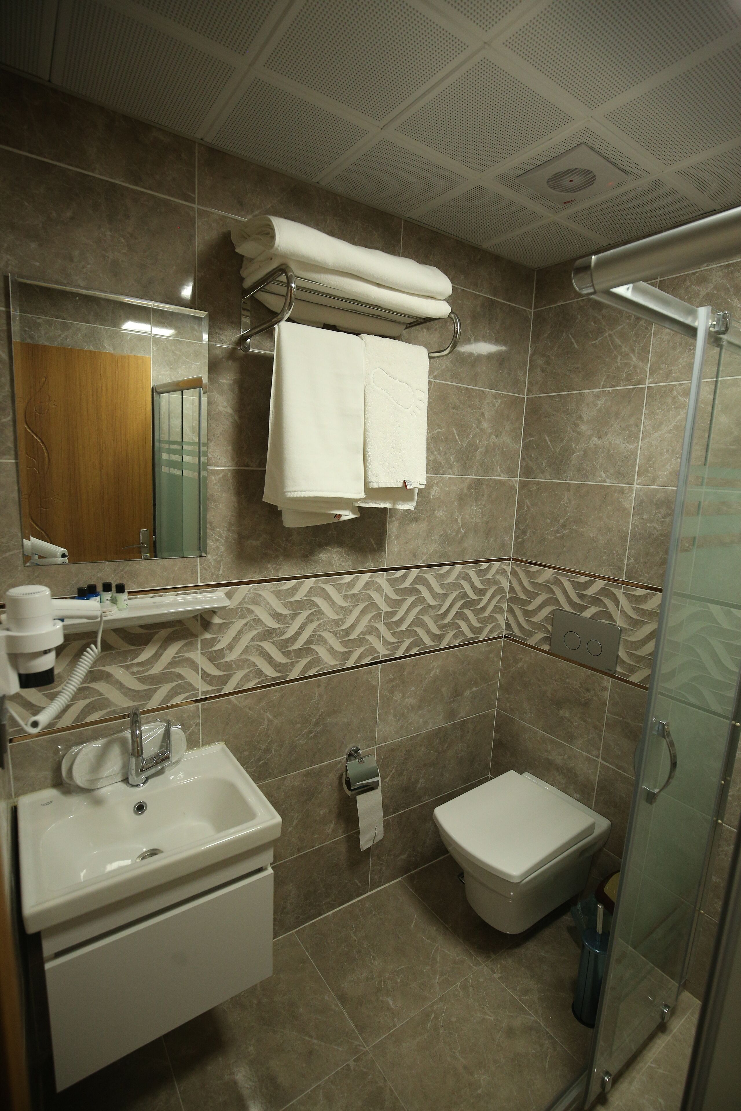 Baño con lavamanos, espejo, toallero, ducha e inodoro.